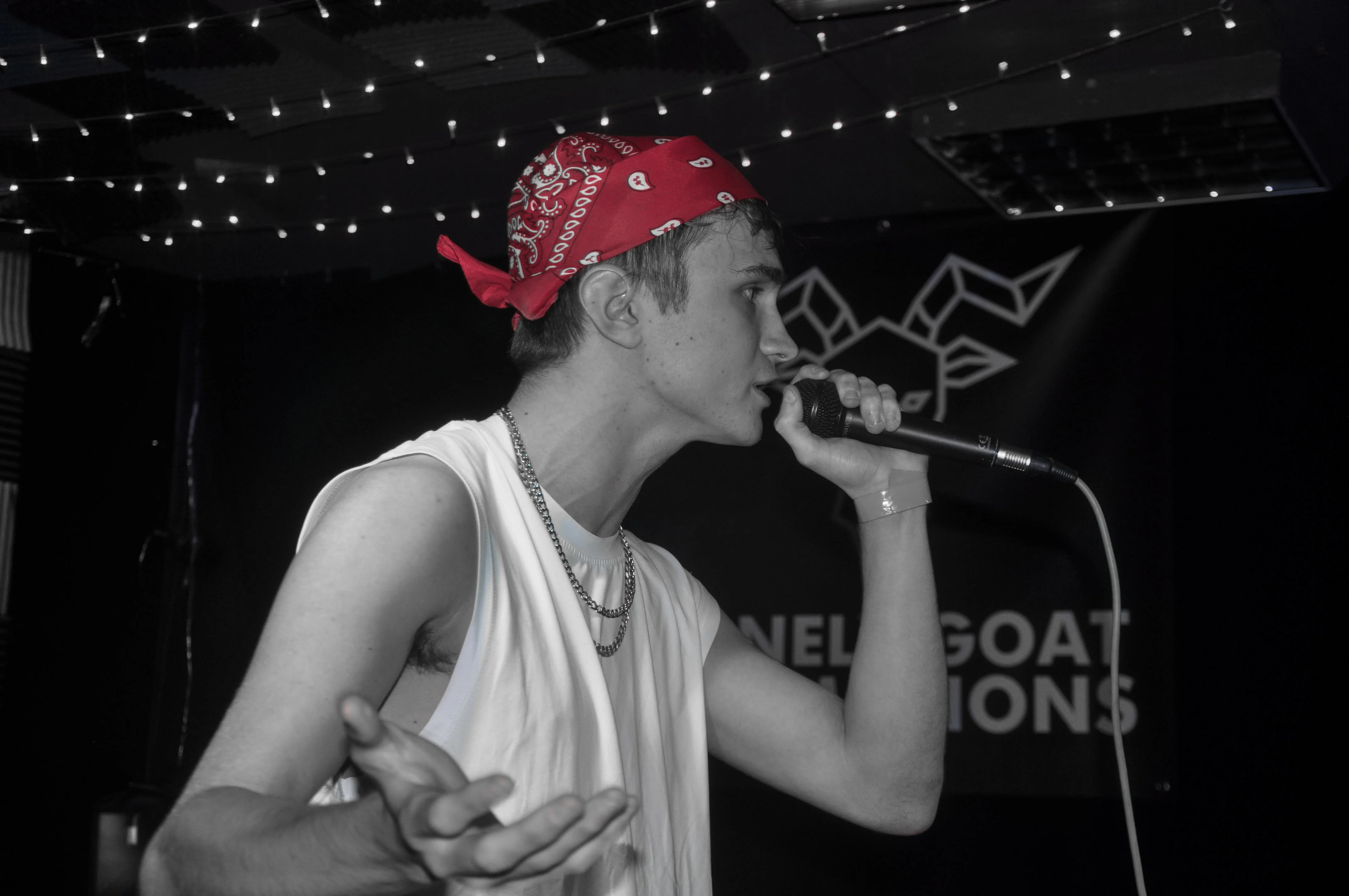 Black and white photo of SHDE at a gig with his red bandana being the only colour visible